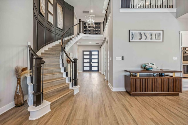 entryway featuring french doors, light wood finished floors, visible vents, stairway, and an inviting chandelier