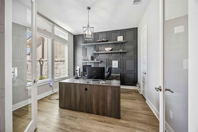 office space with light wood-style floors, baseboards, visible vents, and a notable chandelier