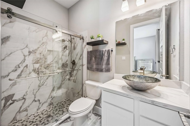 bathroom with marble finish floor, toilet, vanity, and a marble finish shower