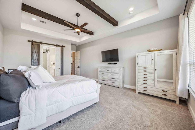 bedroom with a raised ceiling, visible vents, baseboards, and a barn door