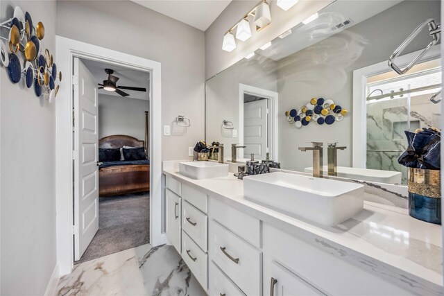 bathroom featuring marble finish floor, double vanity, ensuite bath, and a sink