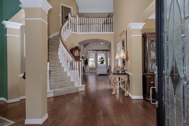 foyer with arched walkways, hardwood / wood-style floors, decorative columns, and baseboards