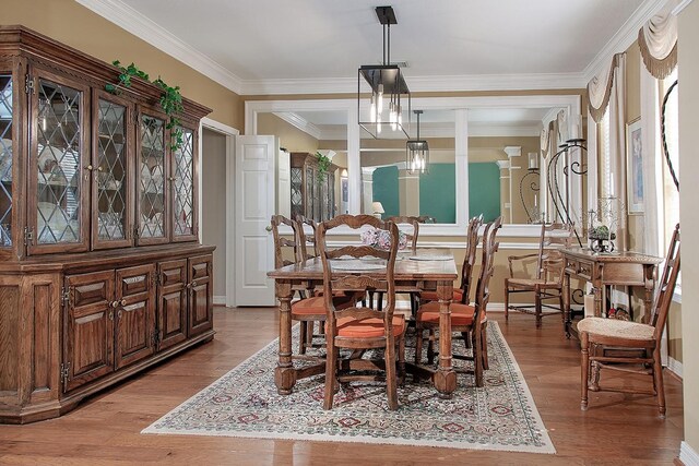 dining area featuring light wood-style floors, ornamental molding, and baseboards