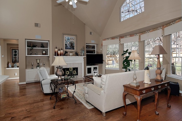 living area featuring a tile fireplace, wood finished floors, visible vents, and baseboards