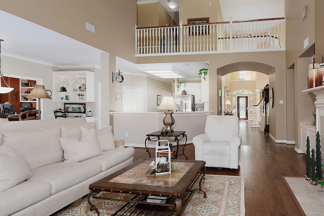 living room with baseboards, visible vents, arched walkways, hardwood / wood-style floors, and crown molding