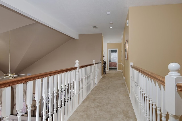 hallway with light carpet, vaulted ceiling with beams, visible vents, and an upstairs landing