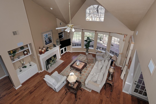 living room featuring built in features, visible vents, a fireplace, and wood finished floors