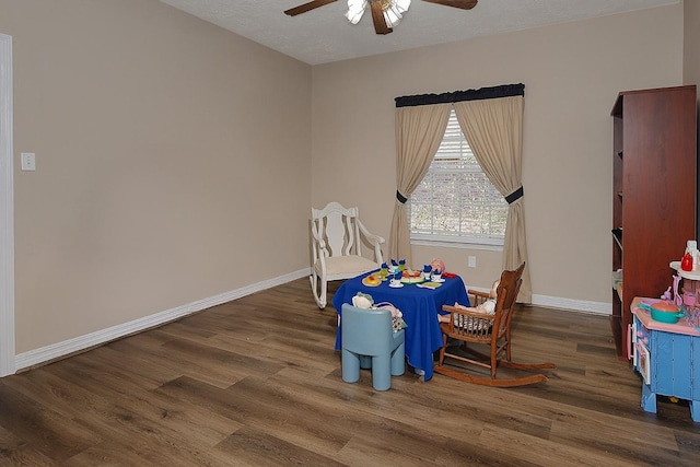 rec room featuring a ceiling fan, a textured ceiling, baseboards, and wood finished floors