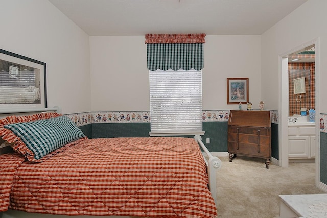 carpeted bedroom featuring ensuite bath and baseboards