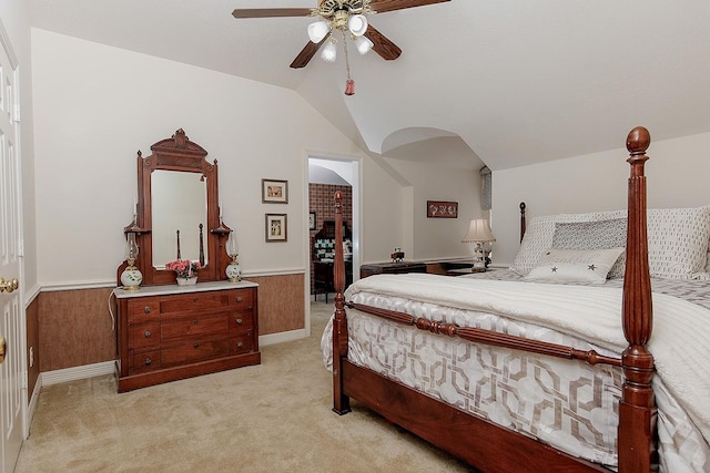 bedroom with lofted ceiling, ceiling fan, light carpet, and wainscoting