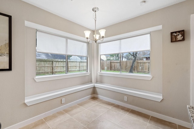 unfurnished dining area featuring baseboards, a notable chandelier, and tile patterned floors