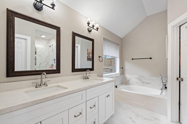 bathroom featuring marble finish floor, a garden tub, vaulted ceiling, and a sink