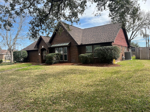 view of front of property with a shingled roof, a front lawn, cooling unit, and brick siding