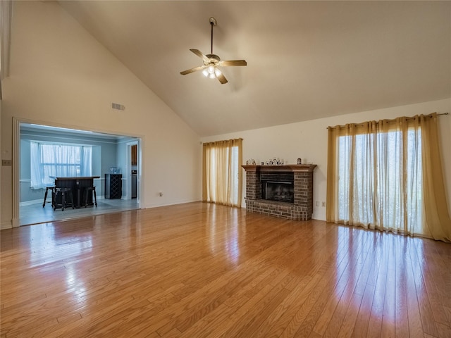 unfurnished living room with ceiling fan, visible vents, a fireplace, and hardwood / wood-style flooring