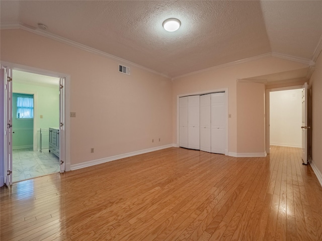 unfurnished bedroom featuring lofted ceiling, light wood finished floors, visible vents, and crown molding