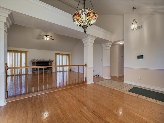 interior space with a ceiling fan, wood-type flooring, a fireplace, and ornate columns