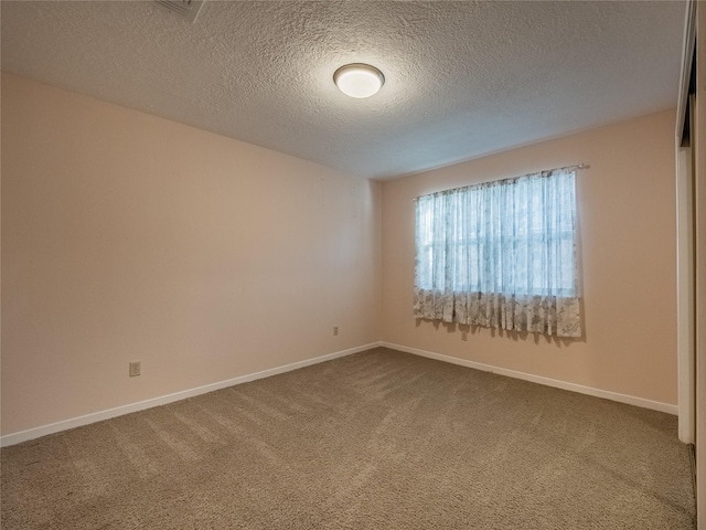 spare room featuring dark carpet, a textured ceiling, and baseboards