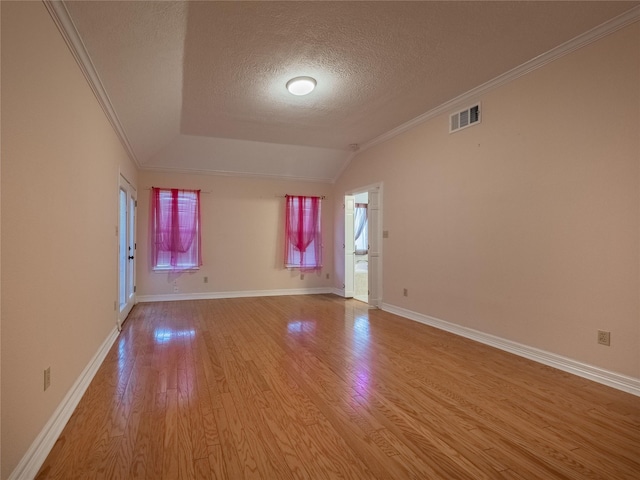 spare room featuring baseboards, visible vents, light wood-style flooring, crown molding, and a textured ceiling