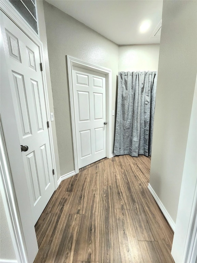 hallway with baseboards and wood finished floors