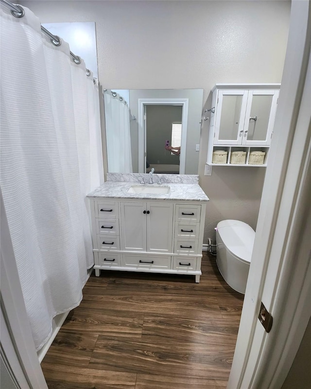 full bath featuring curtained shower, a soaking tub, wood finished floors, and vanity