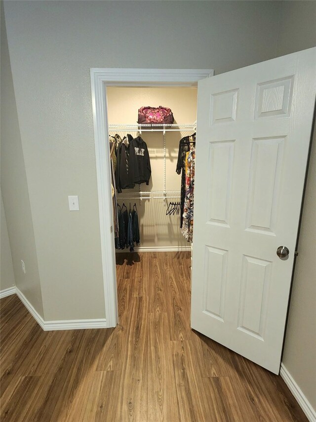 hall with baseboards and wood finished floors