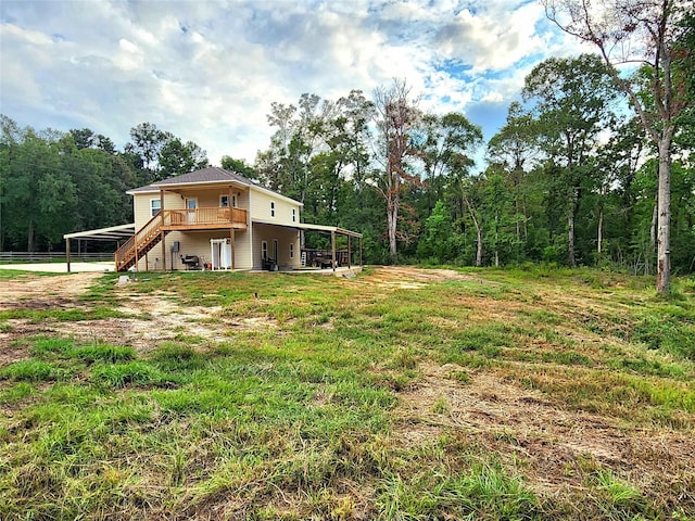 view of yard featuring a view of trees, stairway, and a wooden deck