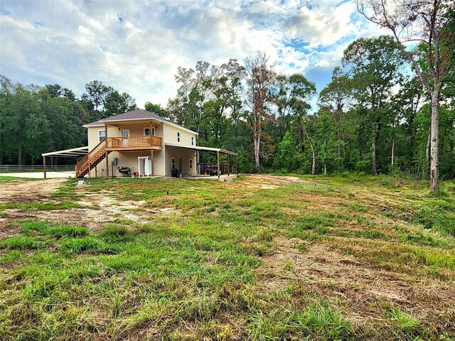 view of yard featuring stairs, a wooded view, a deck, and a carport