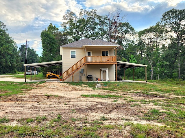 back of property featuring an attached carport, stairs, a deck, and dirt driveway