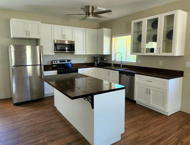 kitchen with a sink, white cabinetry, dark countertops, and stainless steel appliances