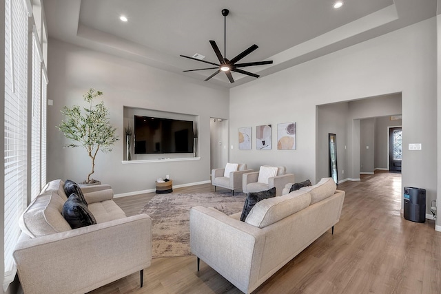 living room featuring light wood-type flooring and a tray ceiling