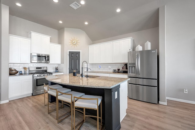 kitchen featuring a sink, visible vents, a kitchen breakfast bar, appliances with stainless steel finishes, and an island with sink