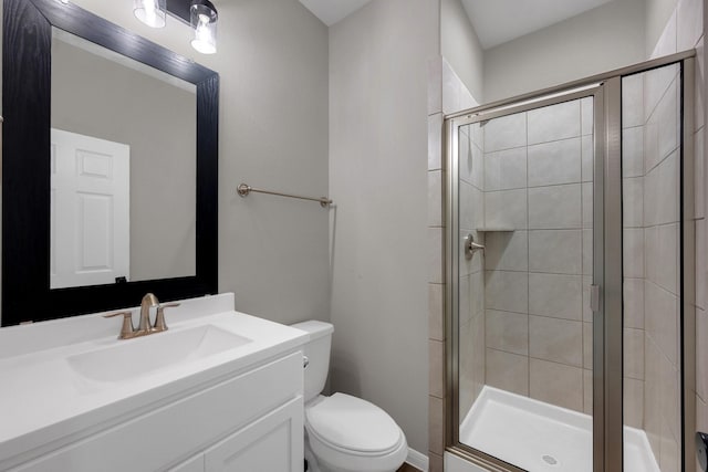 bathroom featuring vanity, a shower stall, and toilet