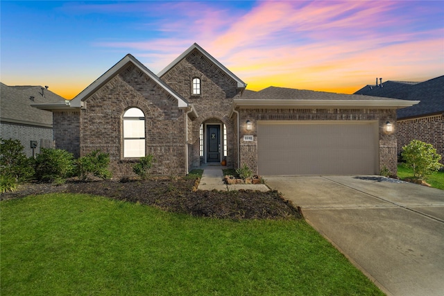 view of front of property featuring an attached garage, a front lawn, concrete driveway, and brick siding