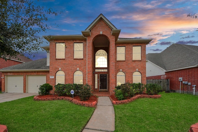 colonial inspired home with an attached garage, brick siding, and a yard