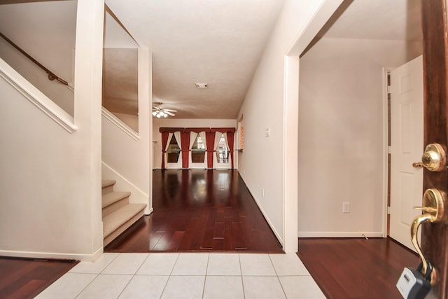 foyer entrance featuring a ceiling fan, tile patterned flooring, baseboards, and stairs