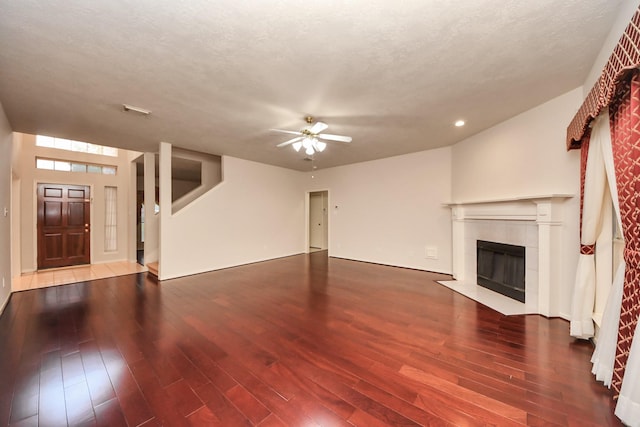 unfurnished living room featuring a textured ceiling, a ceiling fan, wood finished floors, and a tile fireplace