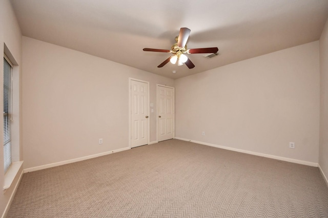 carpeted spare room featuring baseboards, visible vents, and a ceiling fan