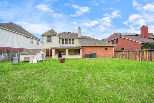 rear view of property with central AC, a shed, a lawn, and a fenced backyard