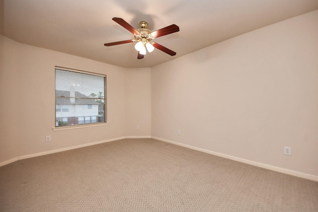 carpeted spare room featuring a ceiling fan and baseboards