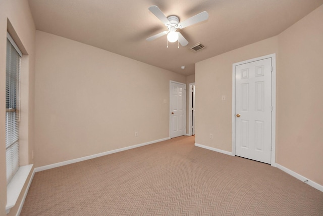 unfurnished bedroom featuring a ceiling fan, light colored carpet, visible vents, and baseboards