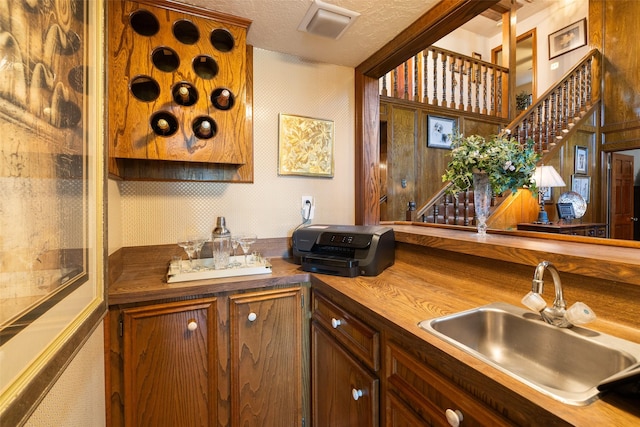 8011 Beaufort Dr, Spring, TX 77379 - kitchen featuring brown cabinetry, a sink, a textured ceiling, wood counters, and wallpapered walls
