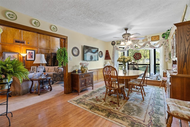 8011 Beaufort Dr, Spring, TX 77379 - dining room with light wood-style floors, a wainscoted wall, a textured ceiling, and a ceiling fan
