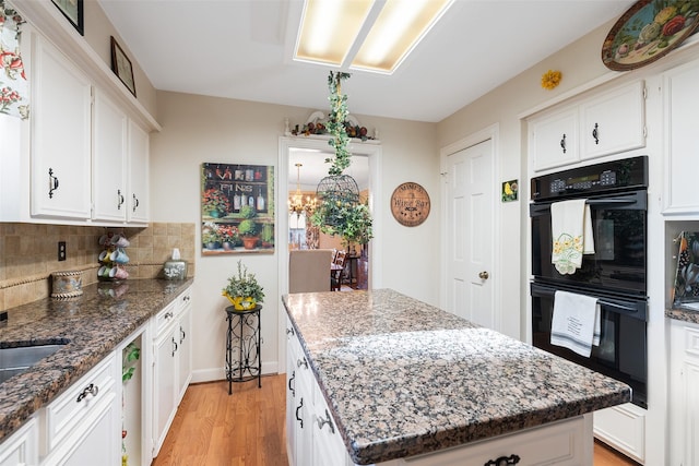 8011 Beaufort Dr, Spring, TX 77379 - kitchen featuring dobule oven black, tasteful backsplash, dark stone countertops, a center island, and light wood-type flooring