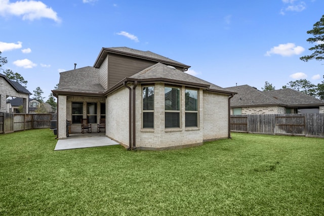 rear view of property with a fenced backyard, brick siding, a shingled roof, a yard, and a patio area