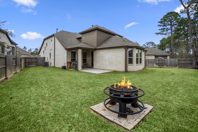 rear view of property featuring cooling unit, a fenced backyard, a yard, and a fire pit