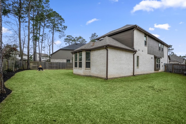 rear view of house featuring a fenced backyard, a lawn, and brick siding