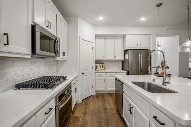 kitchen featuring white cabinets, dark wood-style flooring, stainless steel appliances, pendant lighting, and a sink