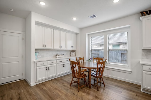 dining room with baseboards, light wood finished floors, visible vents, and recessed lighting