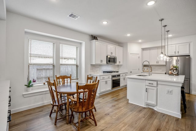 kitchen with appliances with stainless steel finishes, visible vents, a sink, and light wood-style flooring