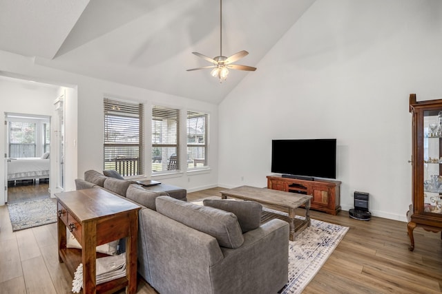 living room with high vaulted ceiling, light wood-type flooring, a wealth of natural light, and baseboards